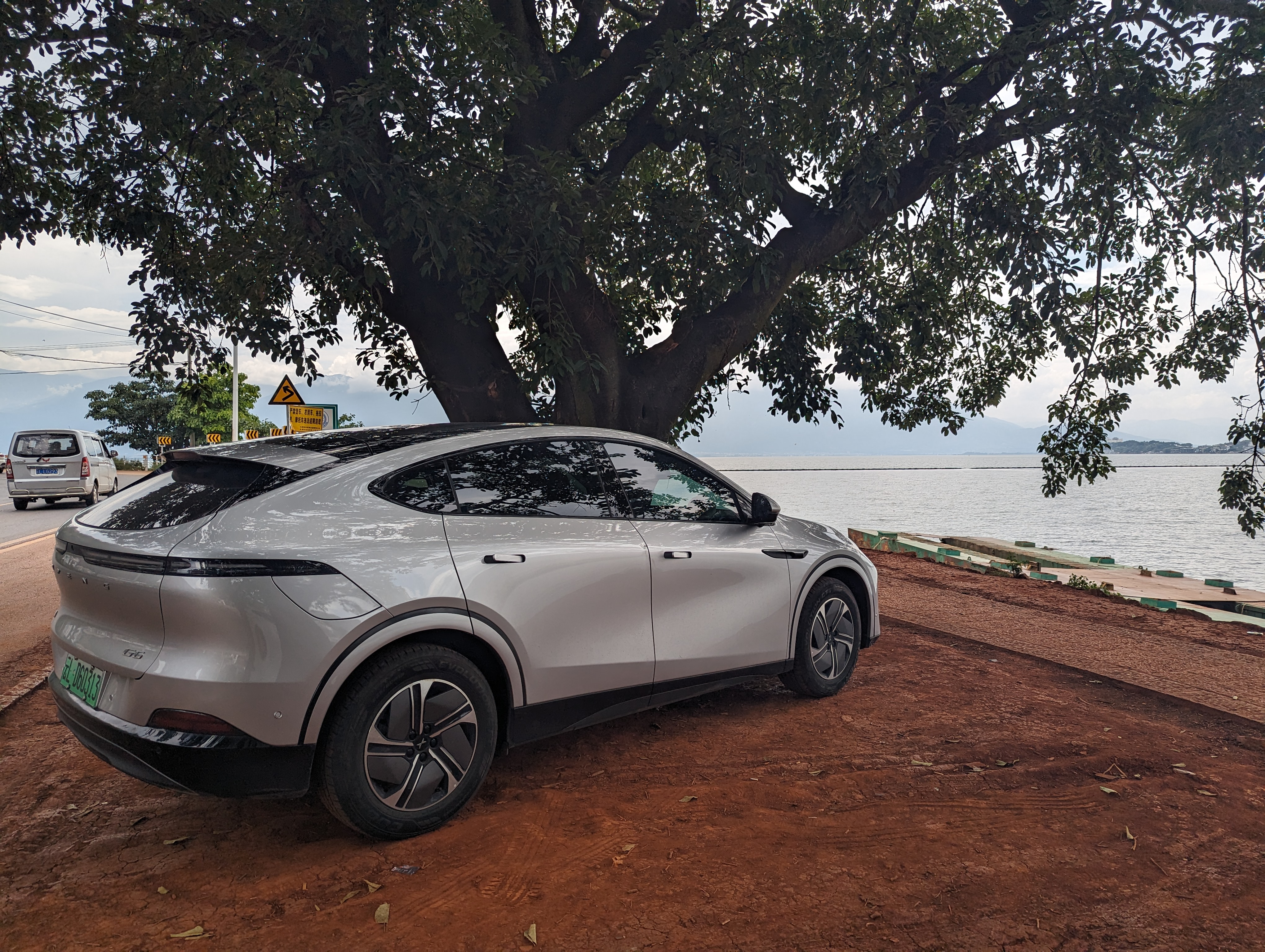 Xpeng G6 relaxing by the water under a tree